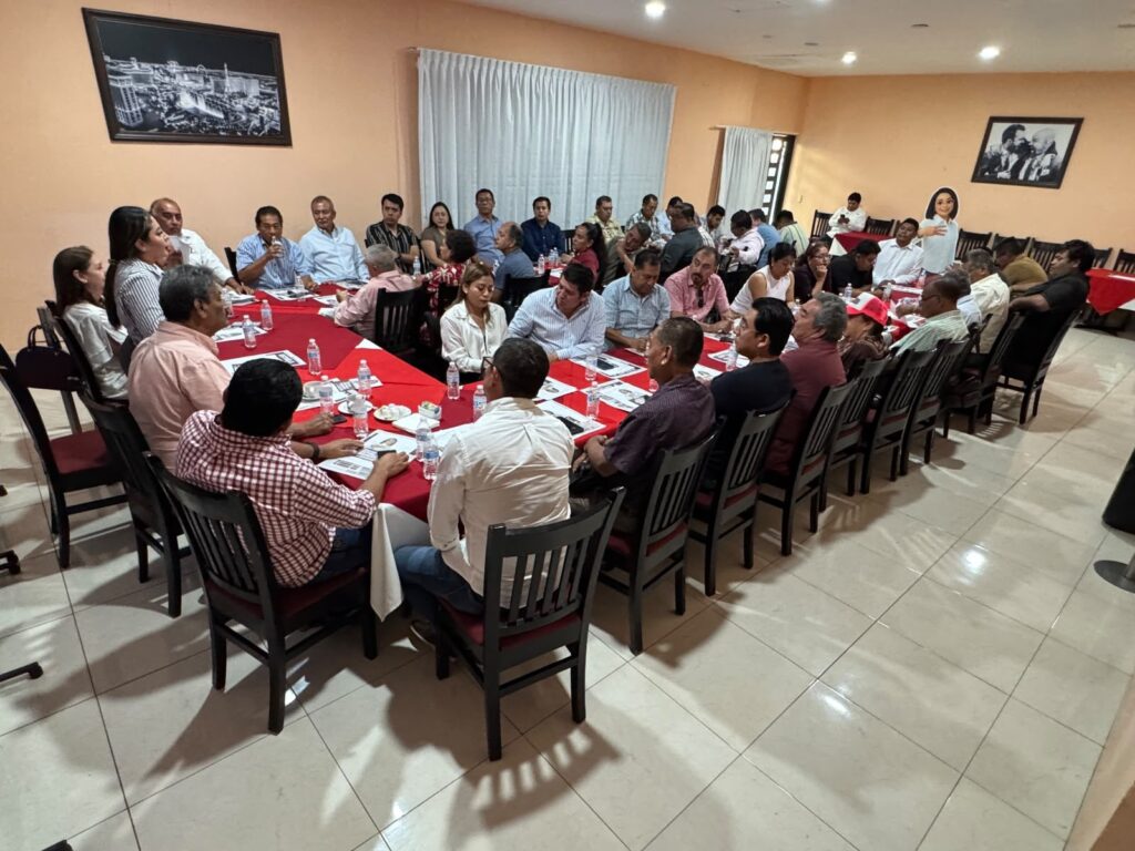 Reunión alrededor de una mesa larga con manteles rojos
