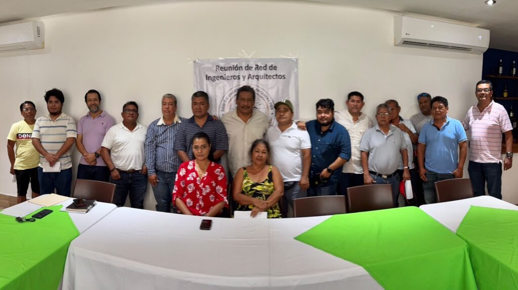 Integrantes de la Red de Ingenieros y Arquitectos de pie detrás de la mesa de trabajo