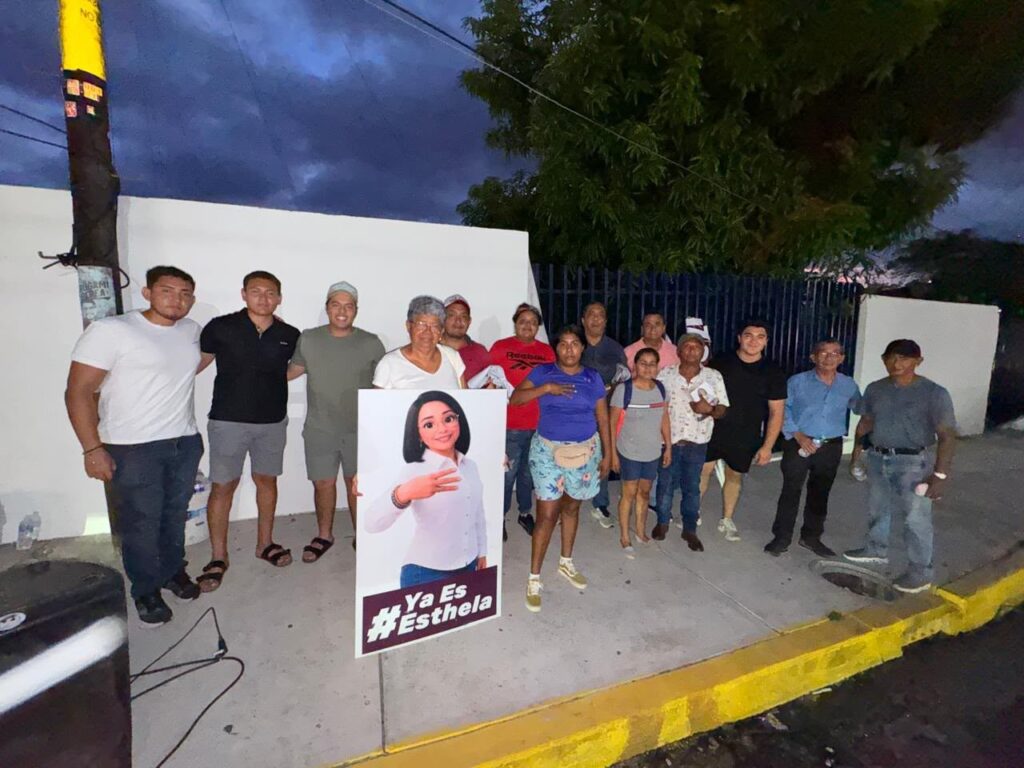 Brigada nocturna con la figura y el lema #YaEsEsthela en una banqueta
