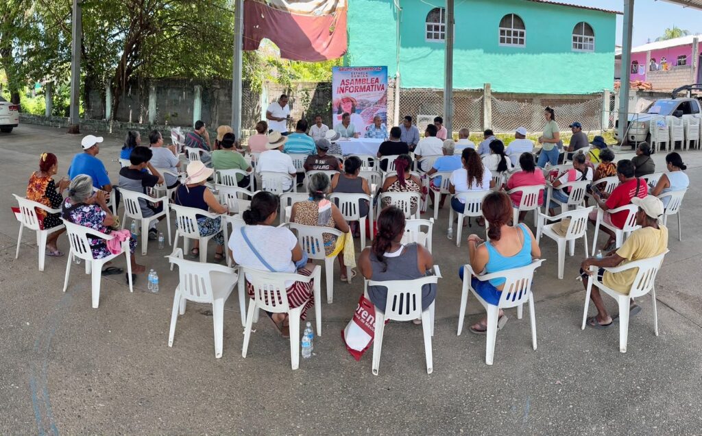 Asamblea informativa al aire libre con vecinos sentados en sillas blancas