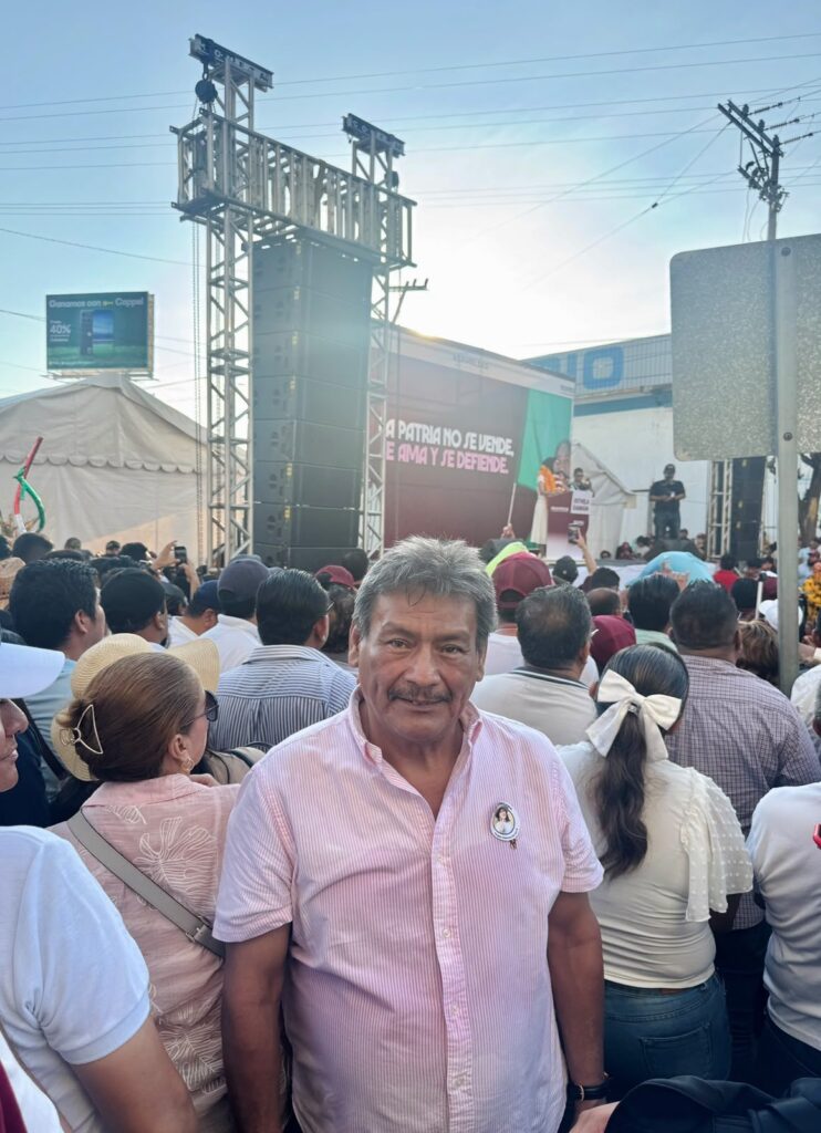 El Ingeniero Arquelao entre la multitud de un evento público, frente al escenario